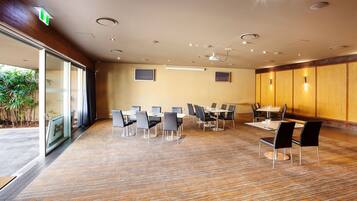 Una sala conferenze con diversi tavoli e sedie, un'ampia finestra con tende e un pannello di parete in legno.