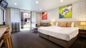Une chambre d’hôtel moderne équipée d’un grand lit, d’un canapé, d’un bureau avec une chaise et d’une télévision.