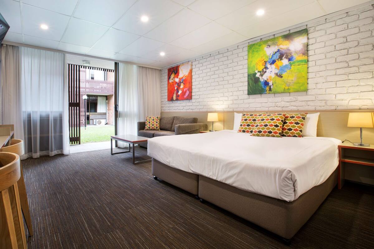 Een moderne hotelkamer met een groot bed, een bank, een bureau met stoel en een televisie.