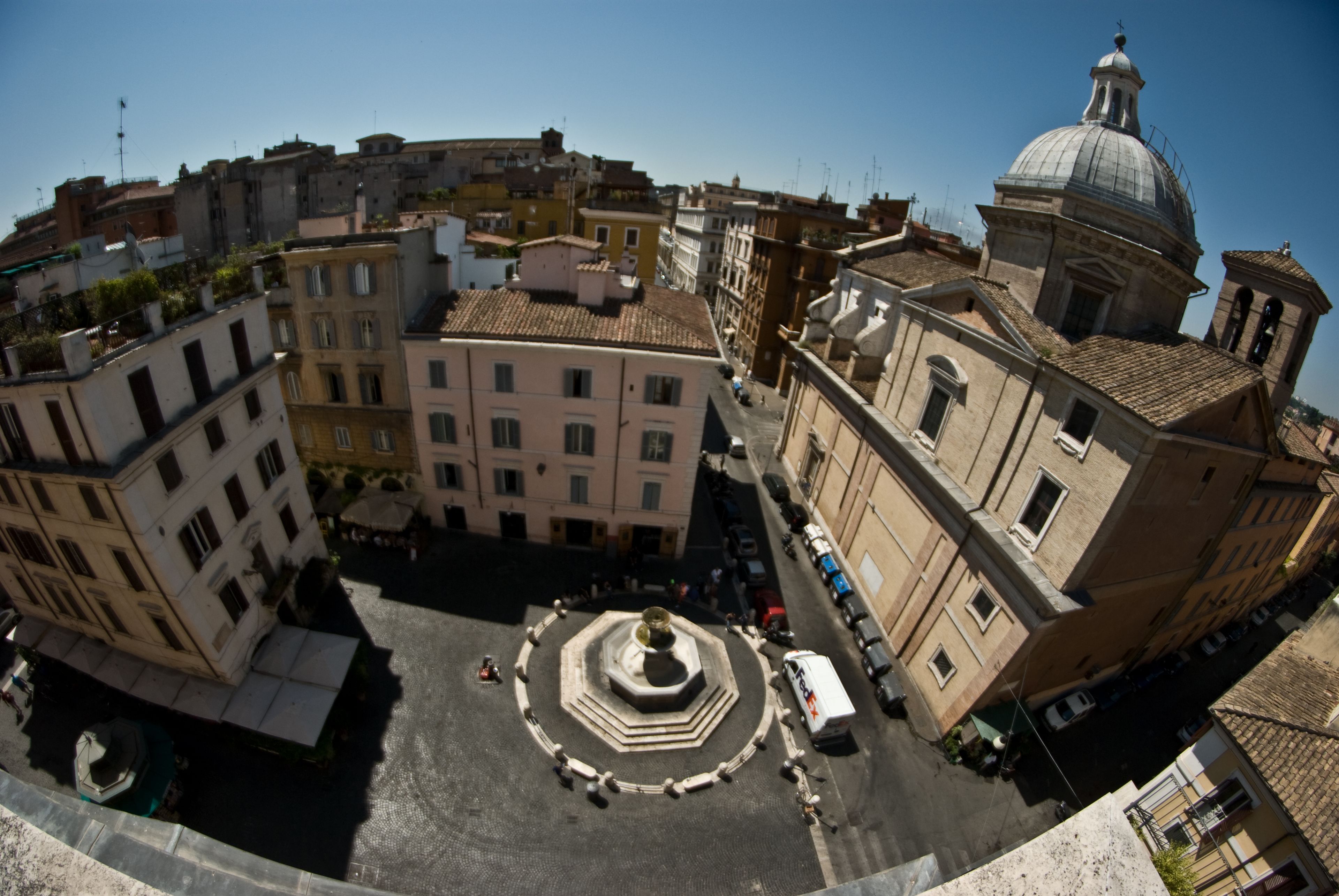 A historic square with a central fountain, surrounded by classical architecture and a prominent dome.