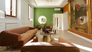 A spacious living room with a large sofa, a coffee table, and a painting on the wall. - Casa Santa Sofia Hotel (Rome)