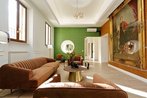 A spacious living room with a large sofa, a coffee table, and a painting on the wall.