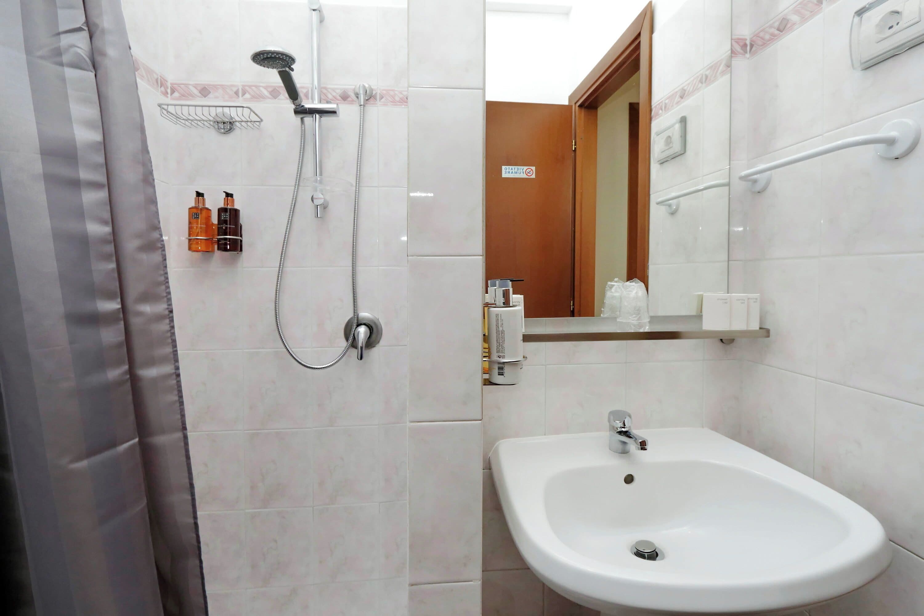 A bathroom with a shower, sink, and toiletries.