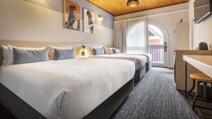 A hotel room with two beds, a desk, and a view of the outside.