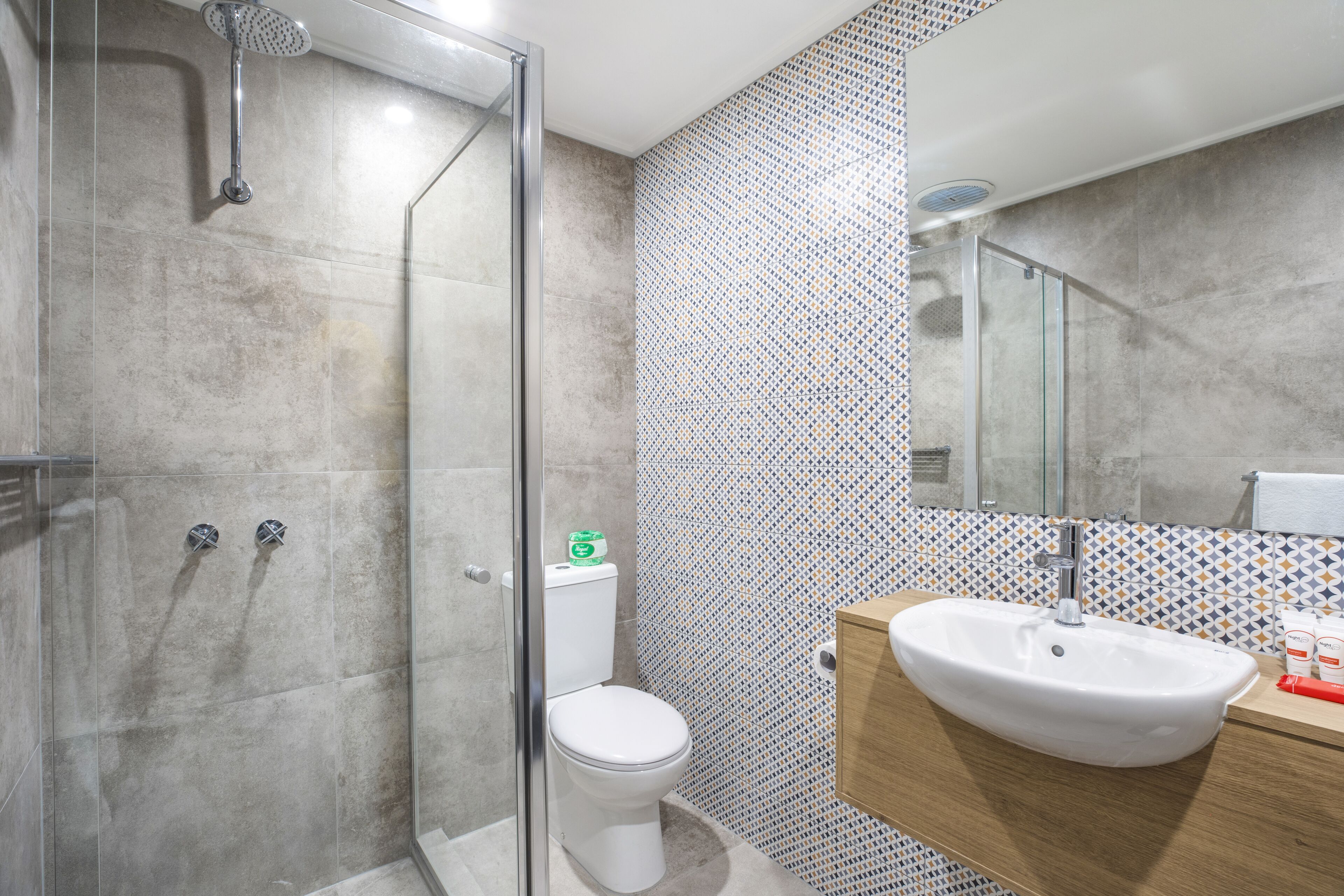 Un baño con ducha, inodoro, lavabo y paredes de azulejos.