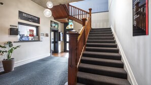 A reception area with a staircase leading to a balcony.