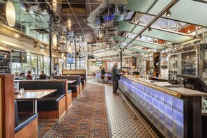 Un restaurante con cabinas, una zona de bar y un suelo estampado.