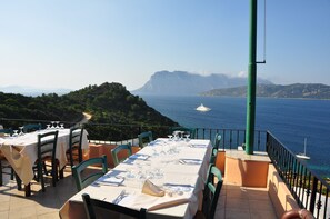 Una mesa lista para comer con vista al mar y a las montañas.
