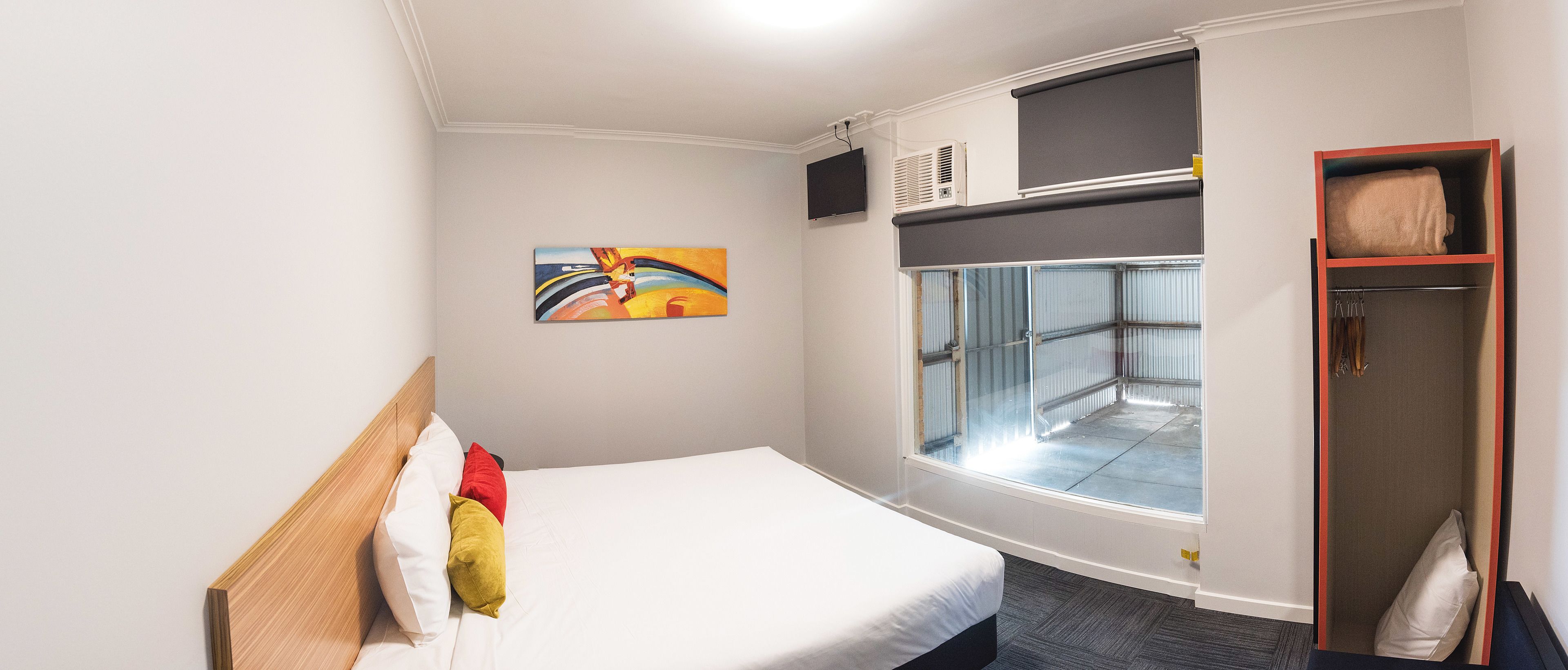 Habitación de hotel con cama, un cuadro, ventana con vistas, aire acondicionado y armario.