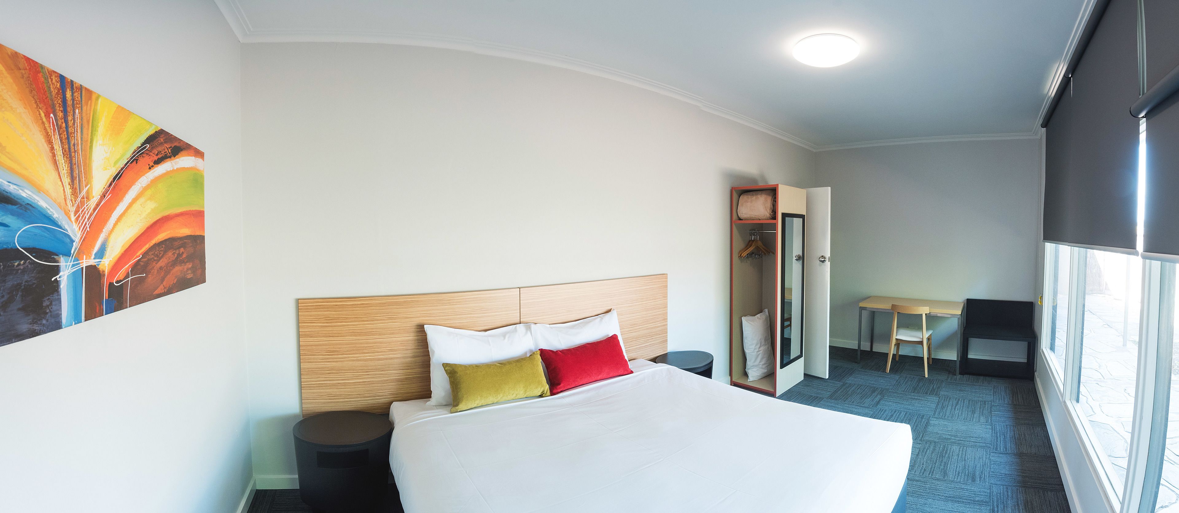 Een hotelkamer met een bed, bureau, stoel en kledingkast.