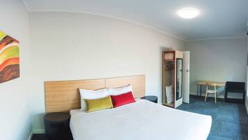 Een hotelkamer met een bed, bureau, stoel en kledingkast.