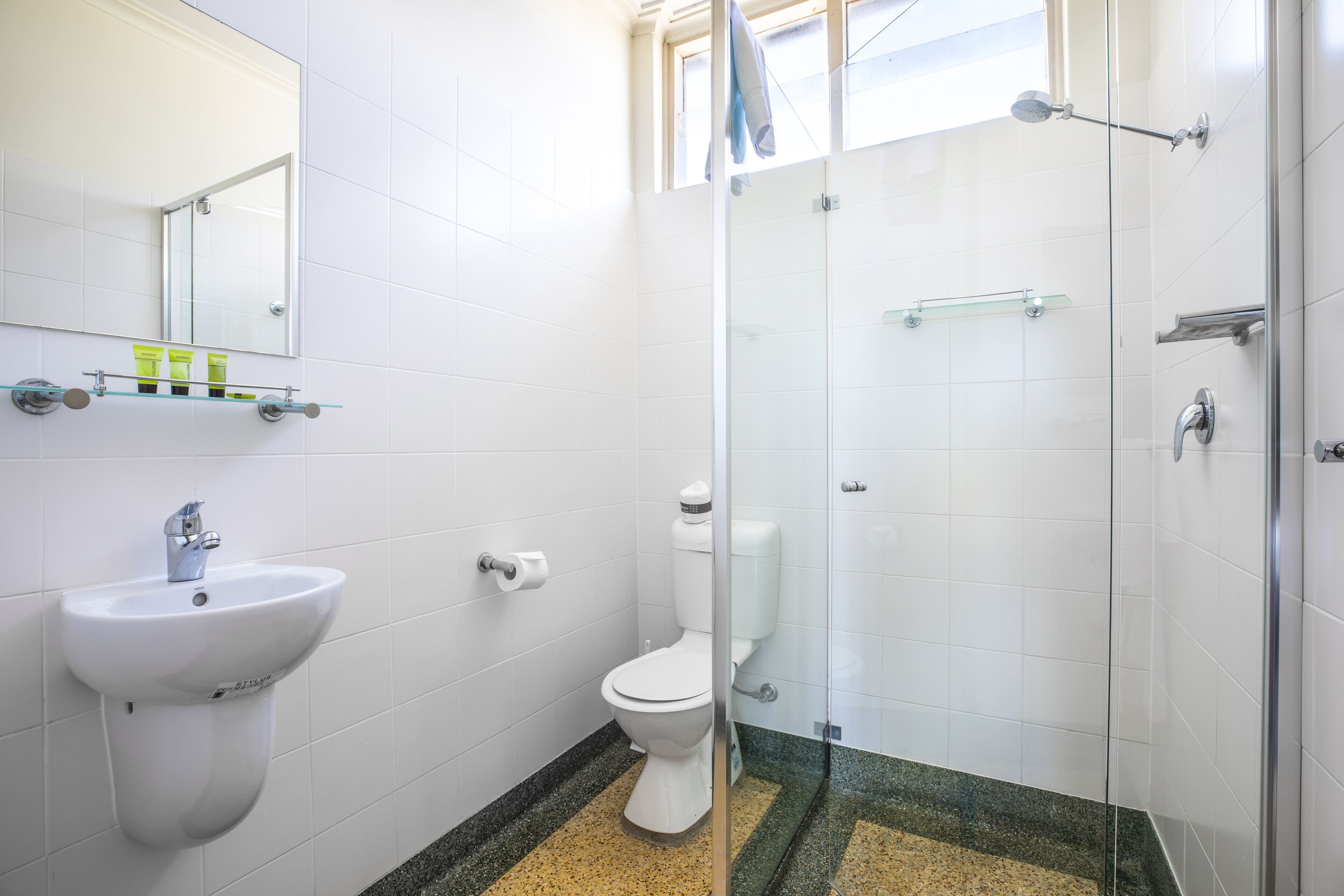 Une salle de bain équipée d’un lavabo, de toilettes et d’une douche à parois en verre.