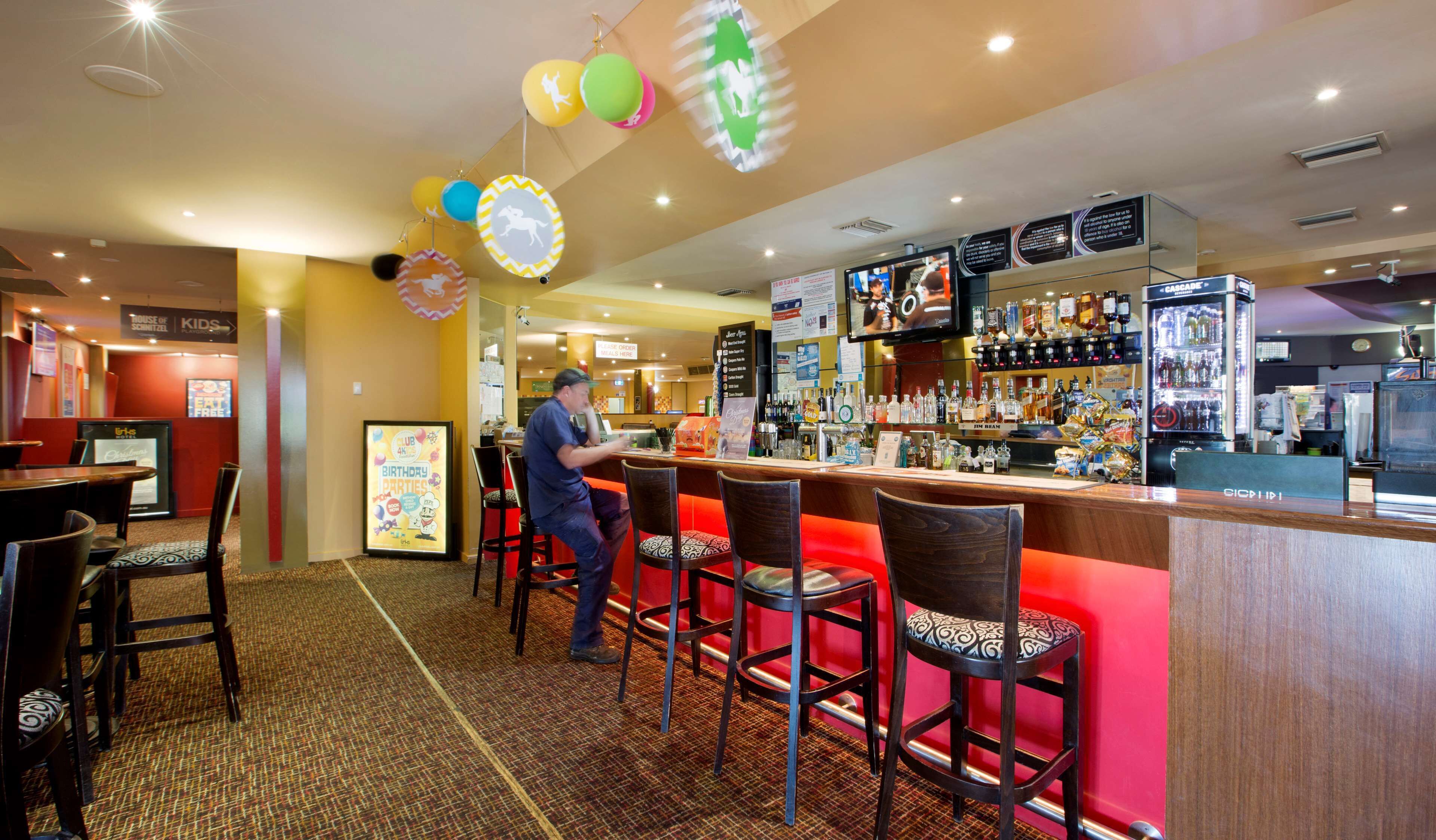 Un espace bar comprenant un comptoir, des tabourets de bar et une variété de bouteilles d’alcool.