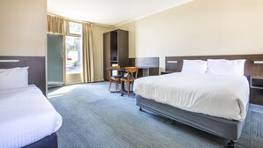 A hotel room with two beds, a desk, and a chair. - Links Hotel (Seaton)