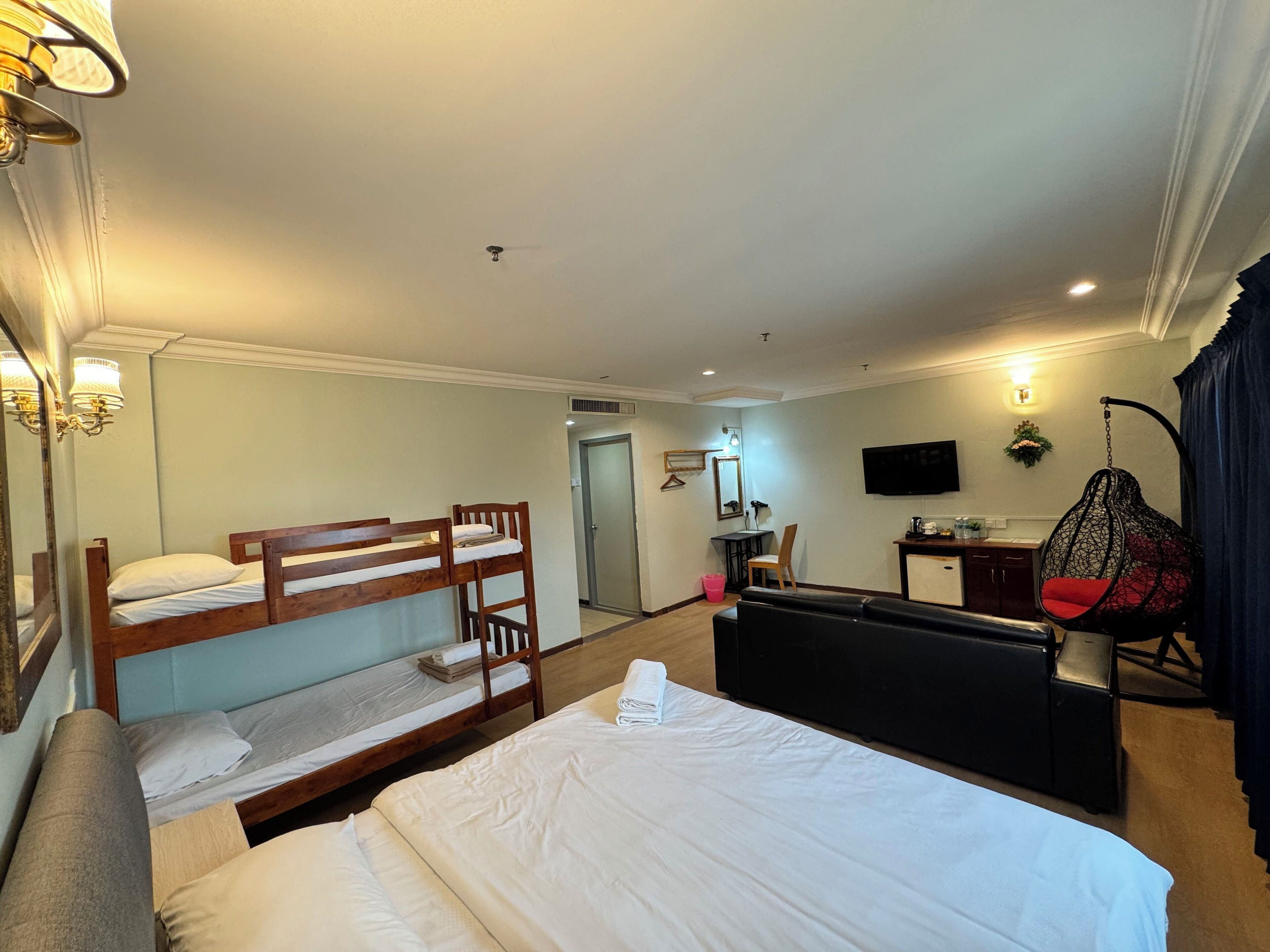 Habitación de hotel con literas, un escritorio, una silla, un televisor y un sillón colgante.