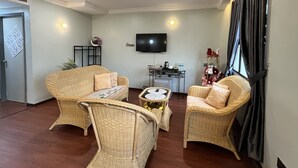 A living room with wicker furniture, a flat-screen TV, and a small table with a remote control.
