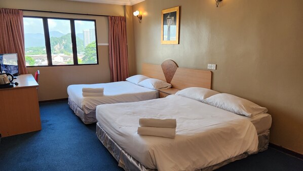 A hotel room with two beds, a desk with a computer, and a view of mountains through the window. - Fair Park Hotel (Ipoh)