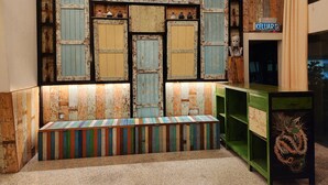 A wall with a rustic, distressed wood panel design, a bench with colorful stripes, and a green shelving unit with a decorative item.