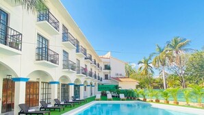 Un hotel con piscina, tumbonas y césped cuidado.