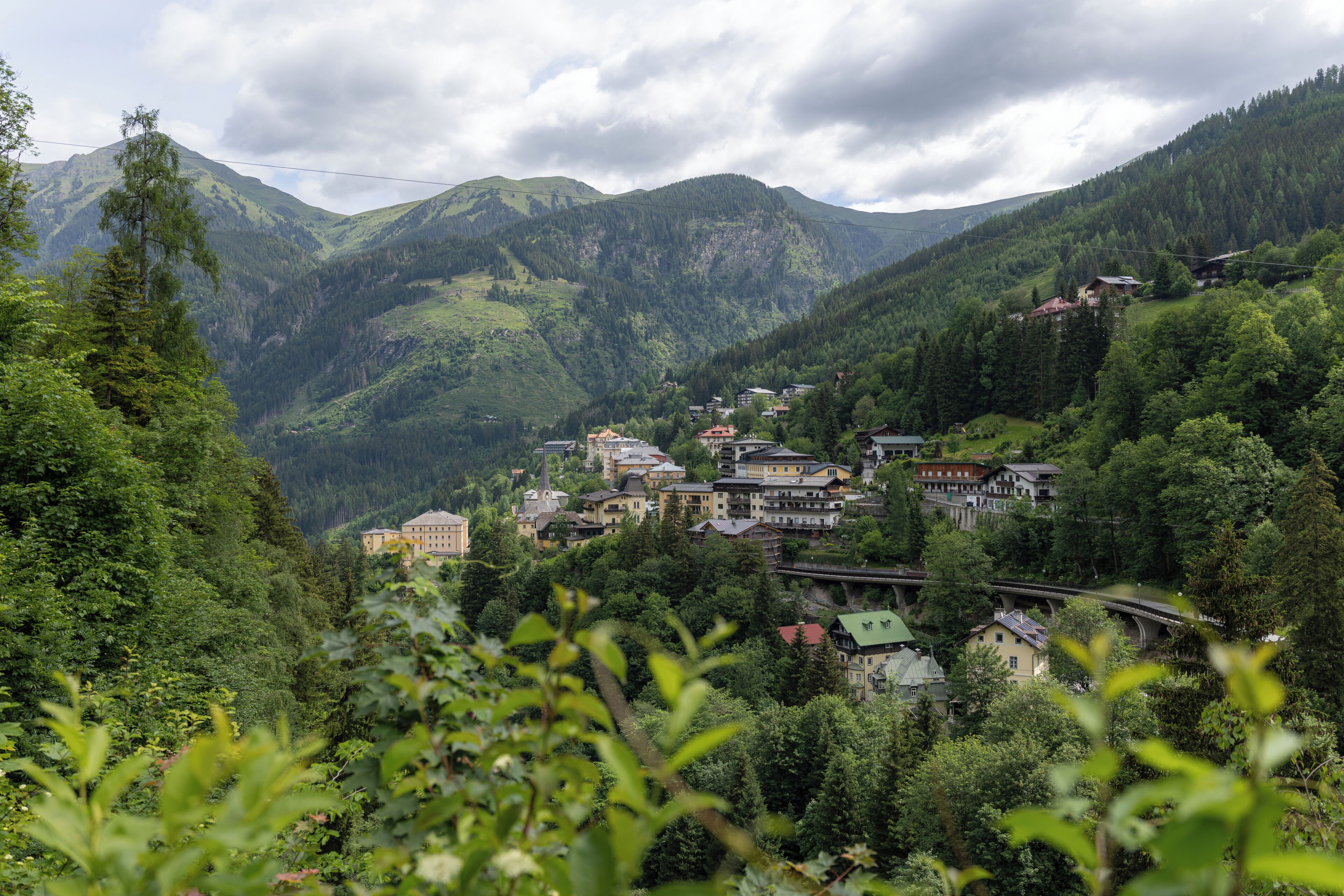 A mountainous village with traditional buildings, a church, and a bridge.