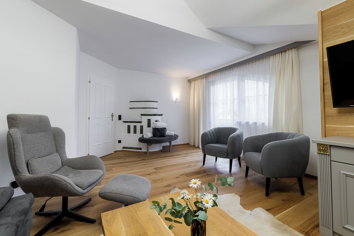 A modern living room with a sofa, armchairs, a coffee table, and a TV mounted on the wall.