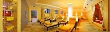 A hotel lobby with a curved ceiling, multiple seating areas with yellow towels, and a reception desk.