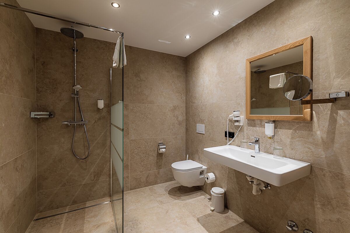 Un baño moderno con cabina de ducha de vidrio, un lavamanos blanco y un espejo grande.