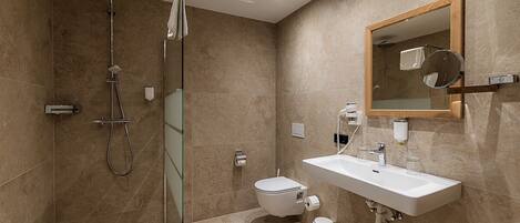 Un baño moderno con cabina de ducha de vidrio, un lavamanos blanco y un espejo grande.