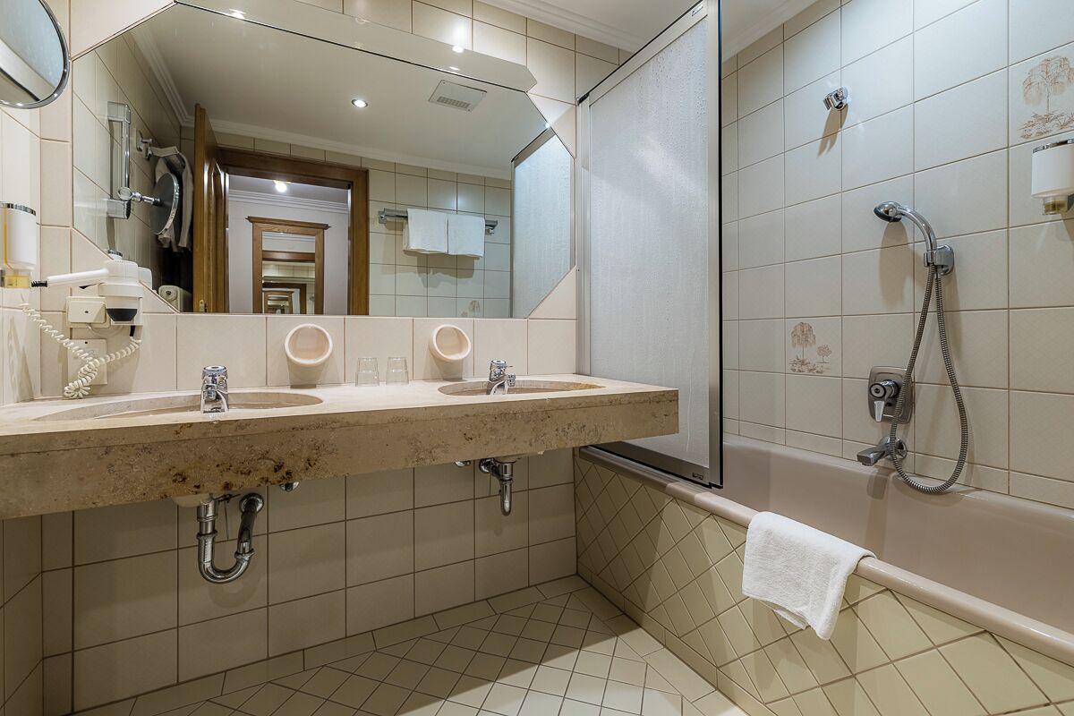A bathroom with two sinks, a mirror, a shower, and a towel rack.