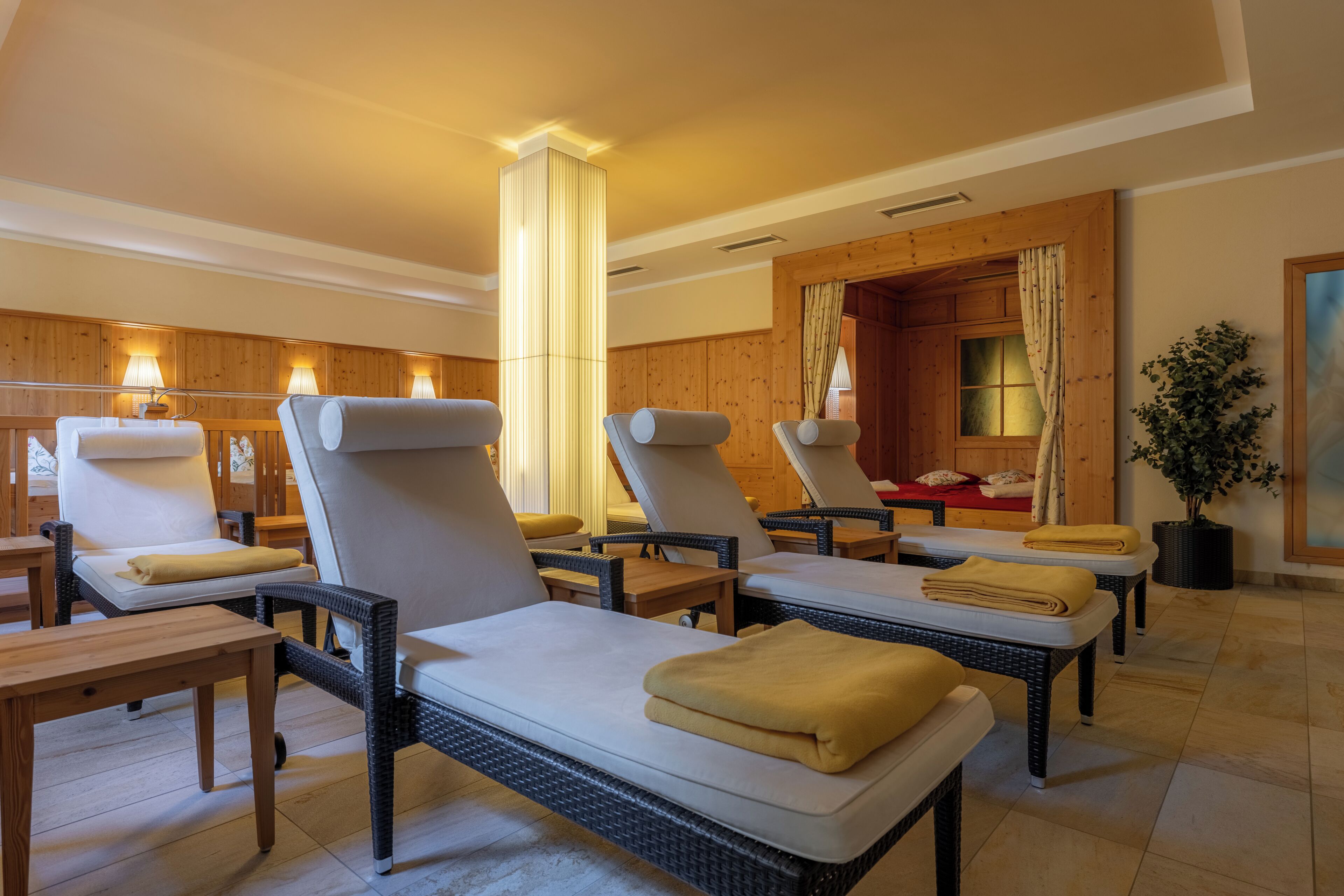 A spa room with massage tables, wooden paneling, and a large pillar.