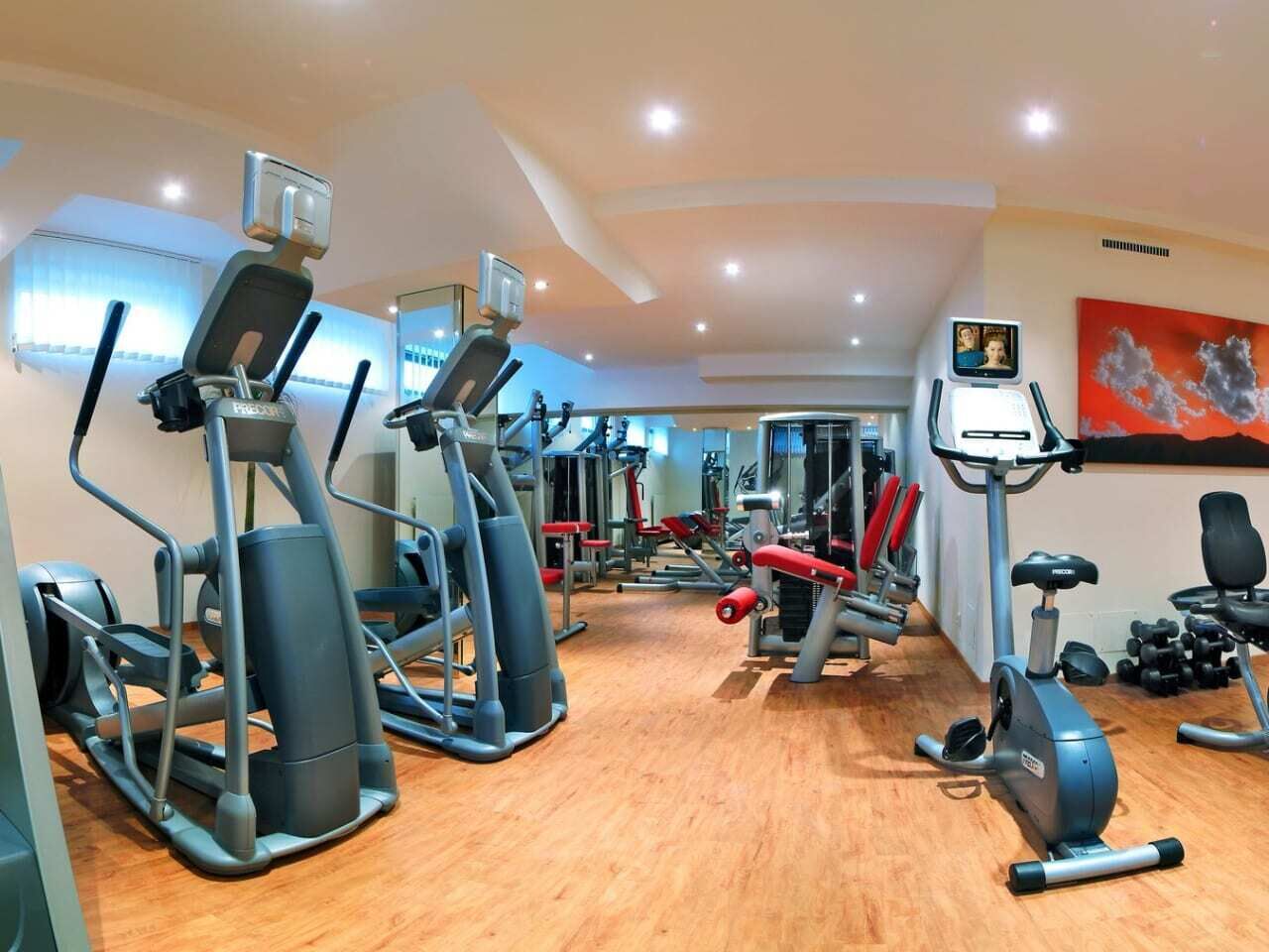 A gym with various exercise equipment, including treadmills, elliptical machines, and weight machines.
