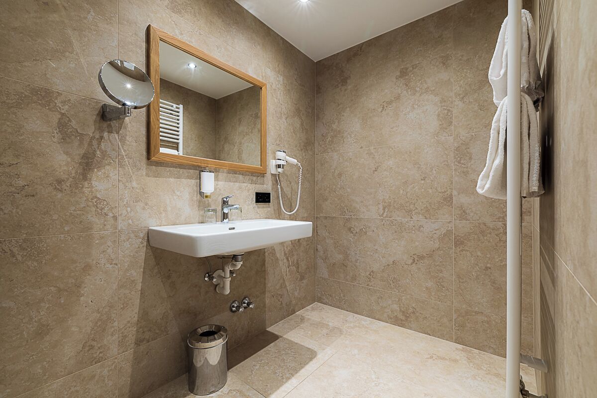 A bathroom with a sink, mirror, towel rack, and shower.