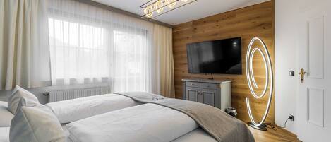Una habitación de hotel moderna con una cama, un televisor, una pared decorativa de madera y una lámpara en el techo.