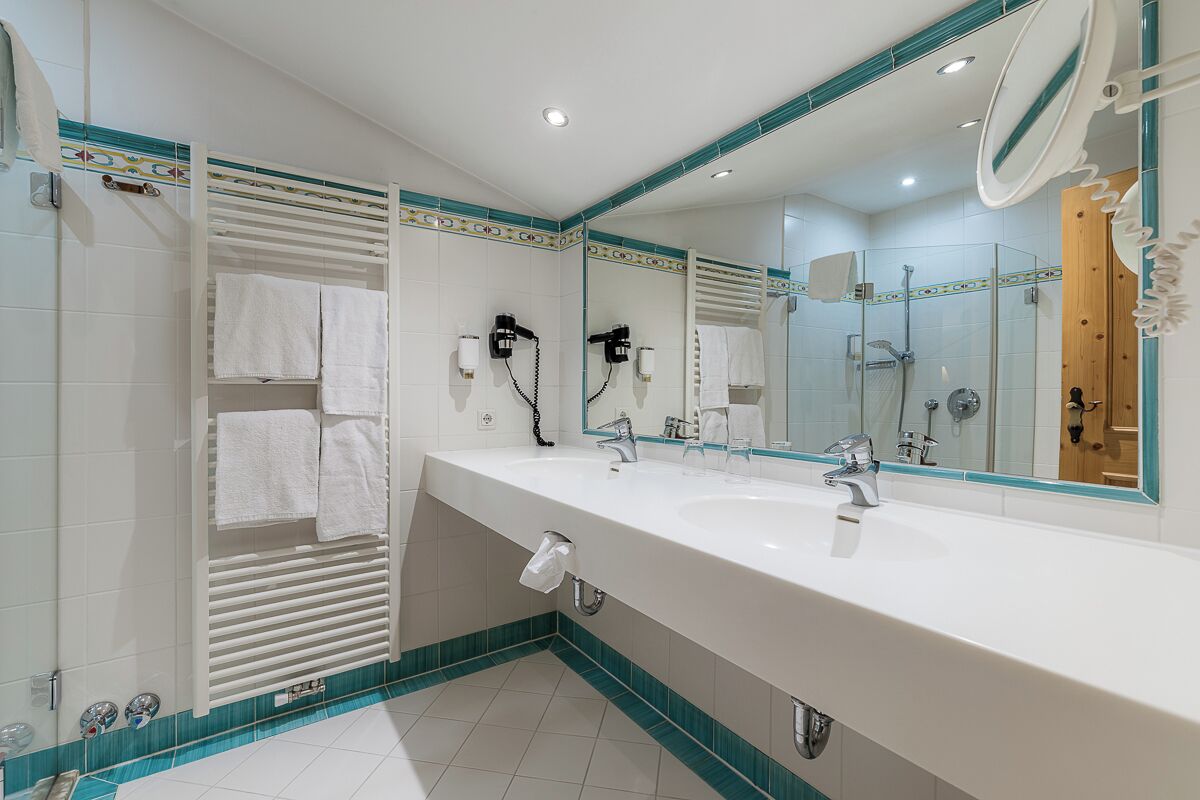 Une salle de bain moderne avec un grand miroir, deux lavabos et un espace douche.