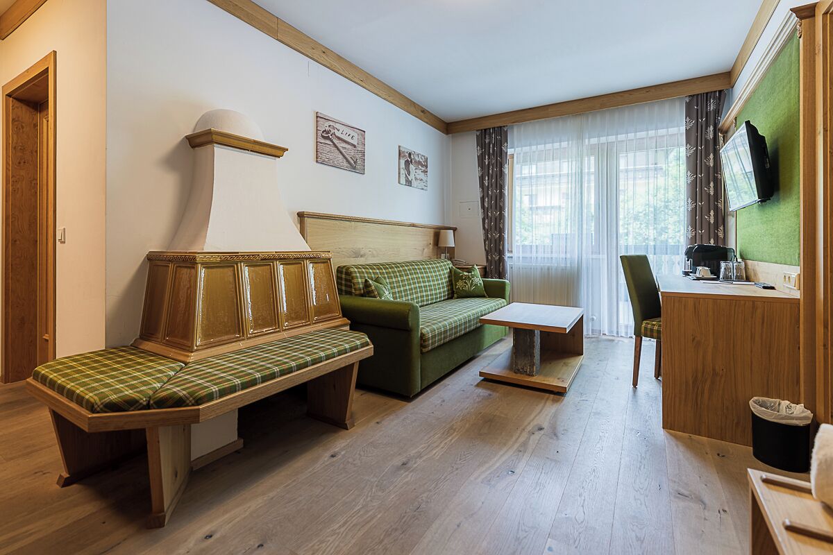 A room with a wooden bench, a green sofa, a small table, and a desk with a chair.