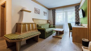 A room with a wooden bench, a green sofa, a small table, and a desk with a chair.