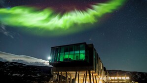 Un edificio moderno de vidrio con una vista despejada del cielo nocturno y las auroras boreales.