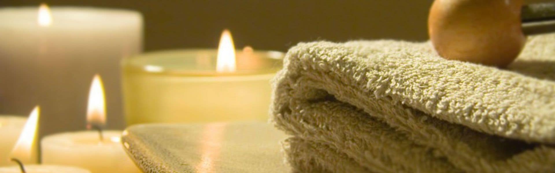 Toallas apiladas y velas encendidas, evocando un ambiente de spa o relajación.