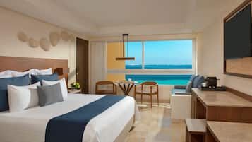 A hotel room with a large bed, a desk, a chair, and a view of the ocean.
