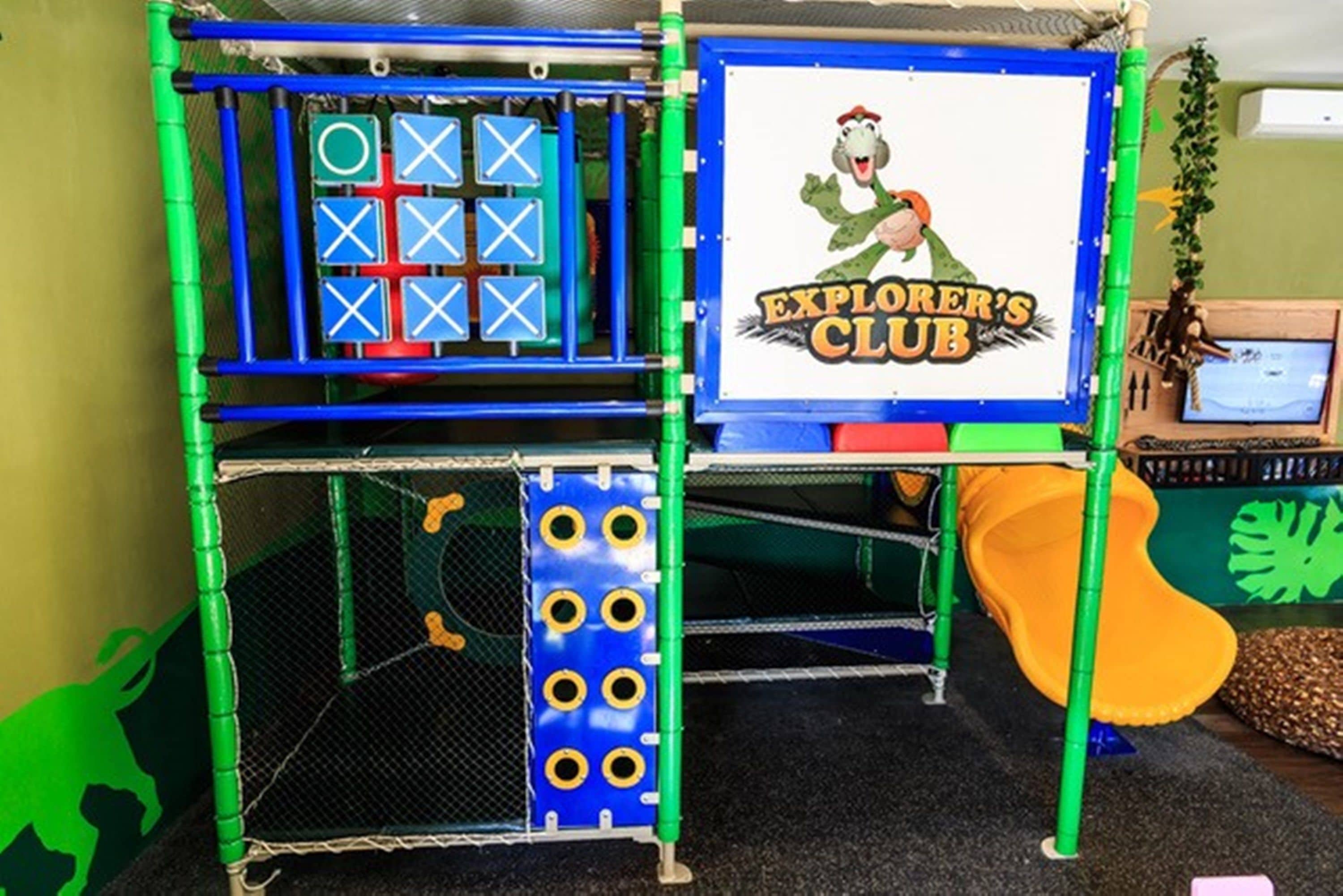 Un área de juegos con una estructura para escalar, un tobogán y un letrero que dice 
