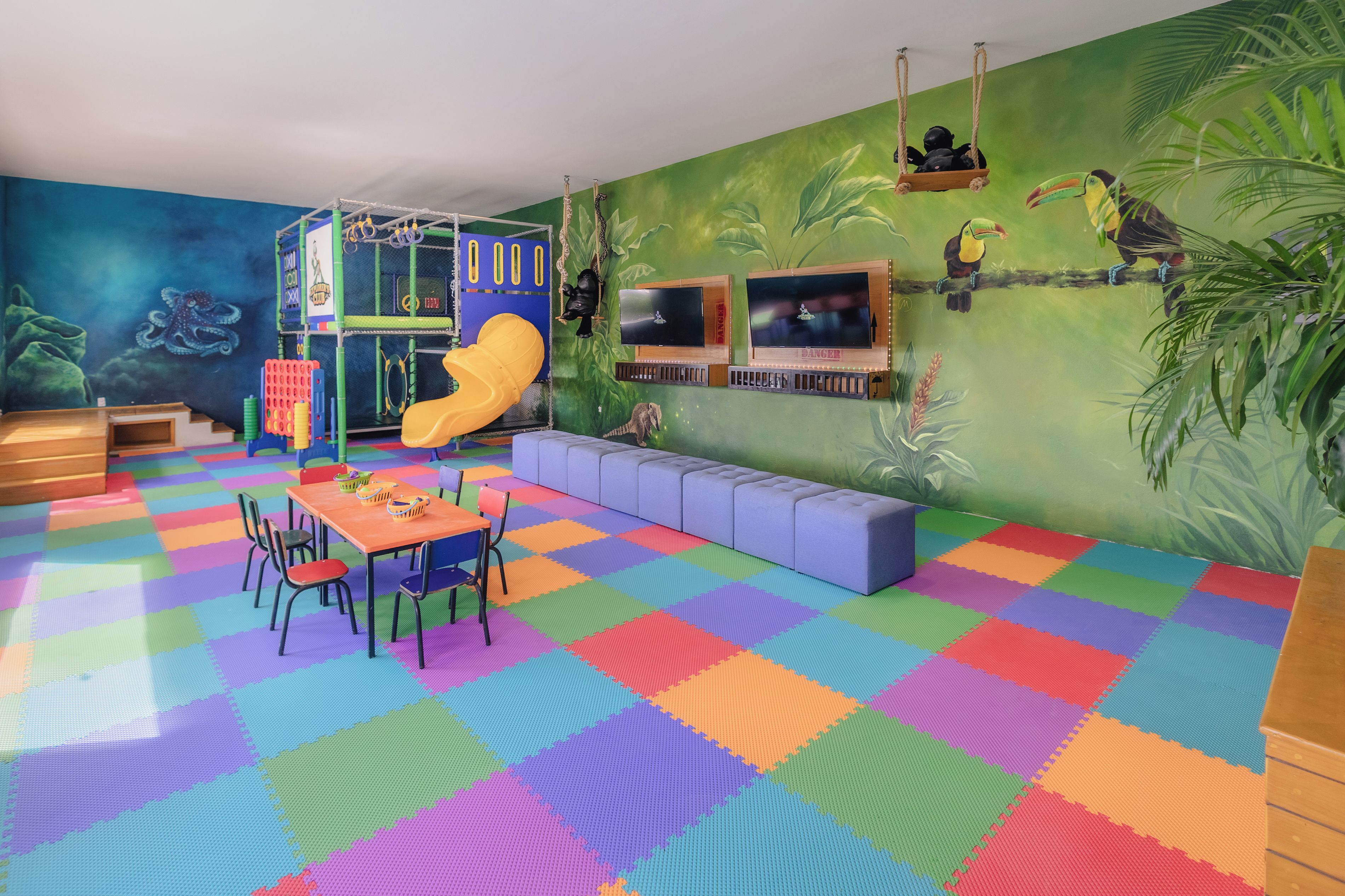A children's play area with a slide, climbing wall, and seating.