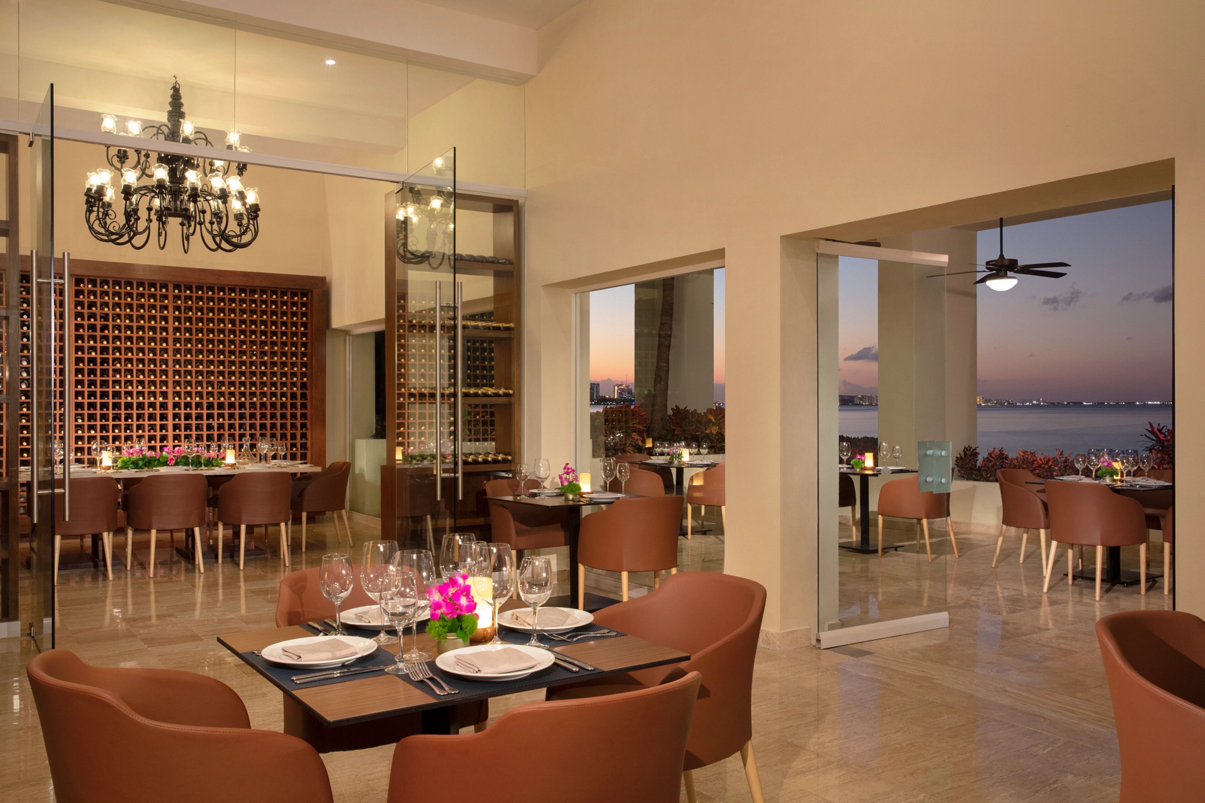 A modern dining area with a view of the city skyline at dusk.