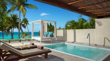Relax by the ocean with a serene pool surrounded by palm trees and a shaded seating area.