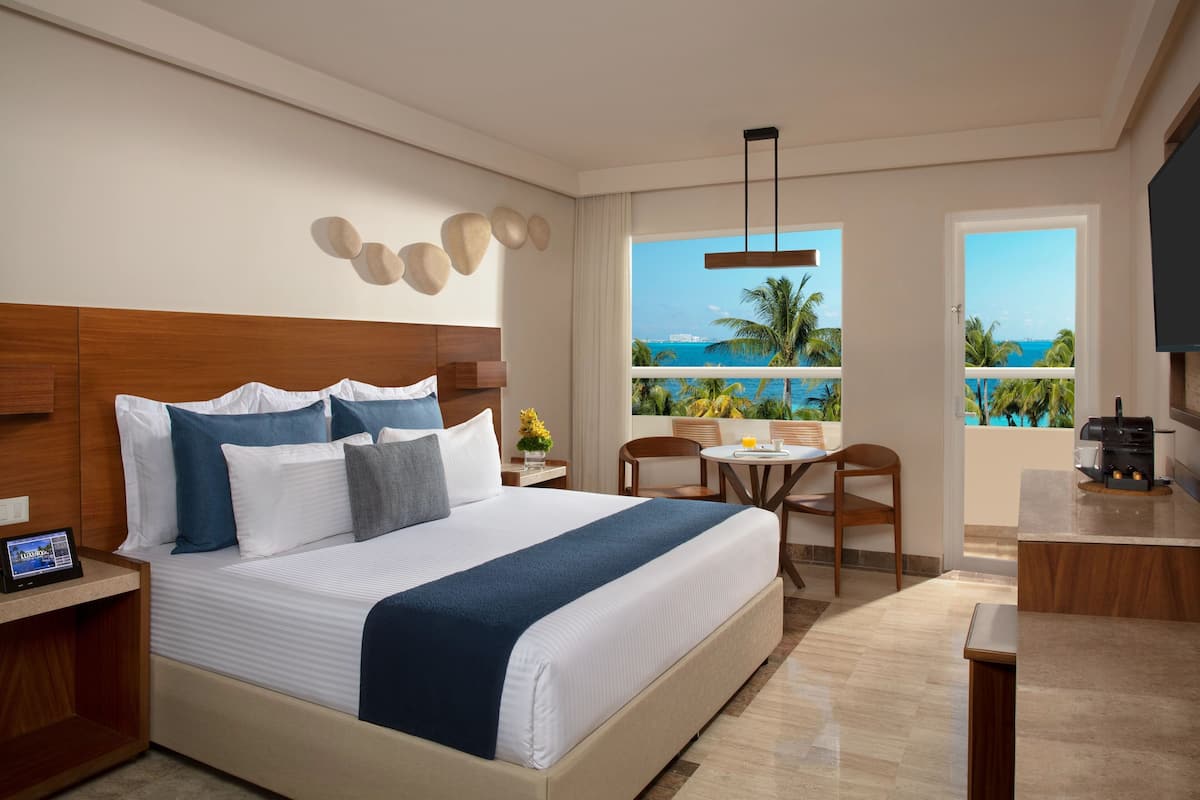 A hotel room with a large bed, a desk, a chair, and a view of the ocean.