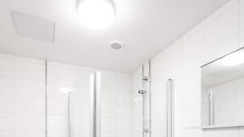 A modern bathroom with a toilet, a glass-enclosed shower, and a sink with a mirror.