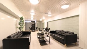 Ein modernes Wohnzimmer mit schwarzen Ledersofas, einem Glastisch und einem Essbereich mit Stühlen und Tisch.