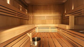 A sauna with wooden benches and a metal bucket.