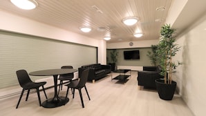 Ein modernes Interieur mit Essbereich, Sofas, einem Flachbildfernseher und Topfpflanzen.