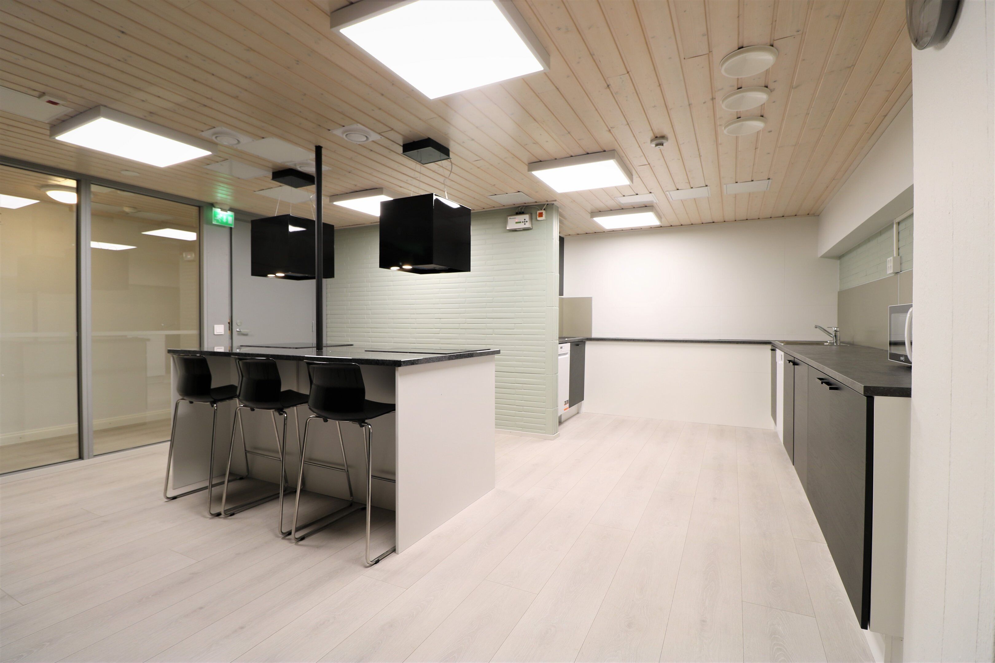 Una cocina moderna con barra, techo de madera y suelo de tonos claros.