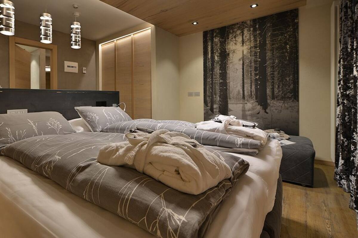 A modern bedroom with a large bed, bedside tables, and a wardrobe.